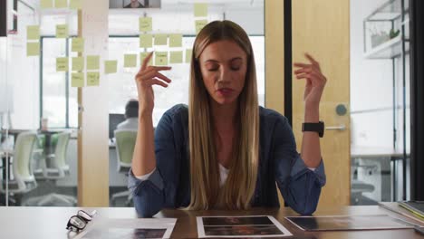 caucasian businesswoman sitting at desk talking and gesturing during video call in office