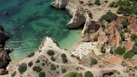 incredible tilt up reveal of local portuguese families on a private secret beach surrounded by clear green ocean water