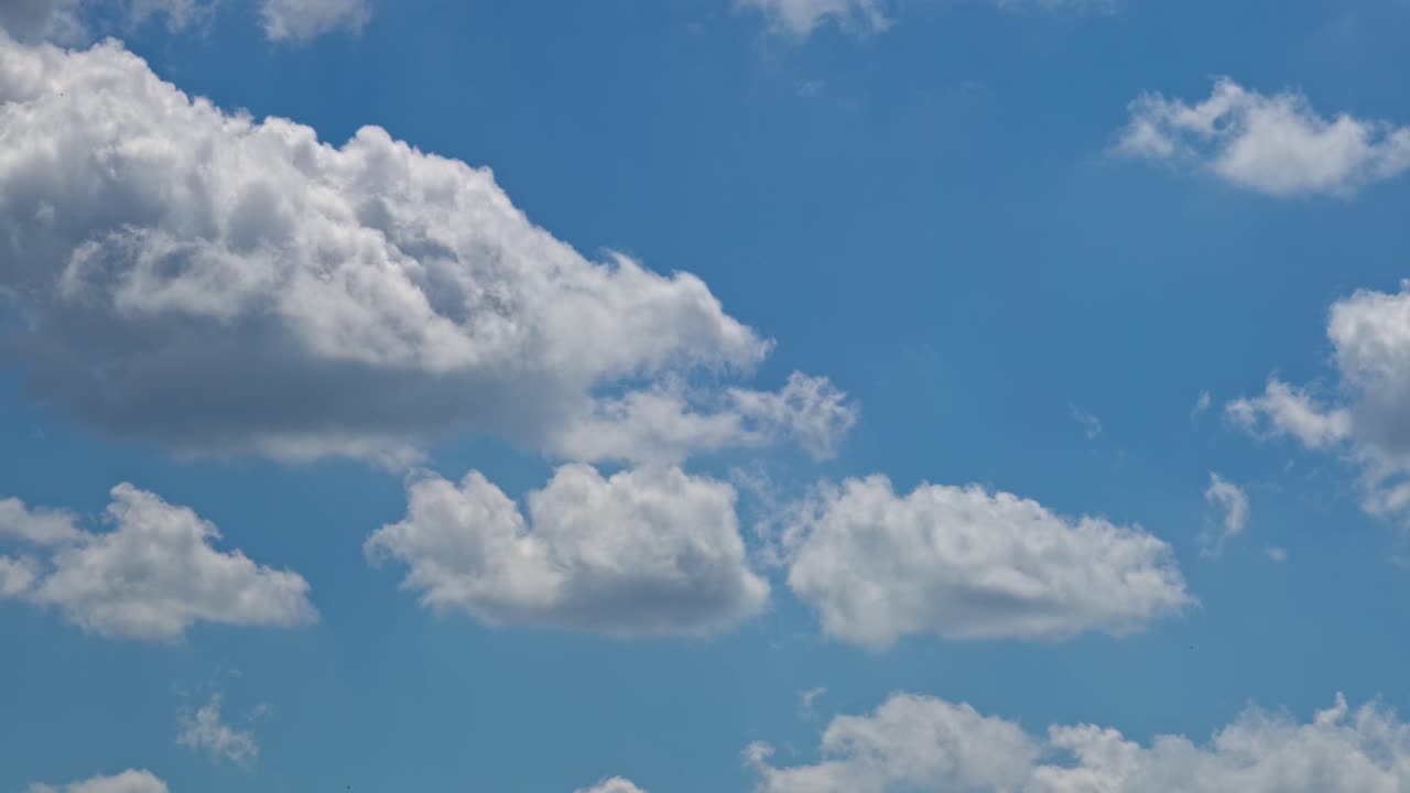 Clouds float in a clear sky during the day with blue background