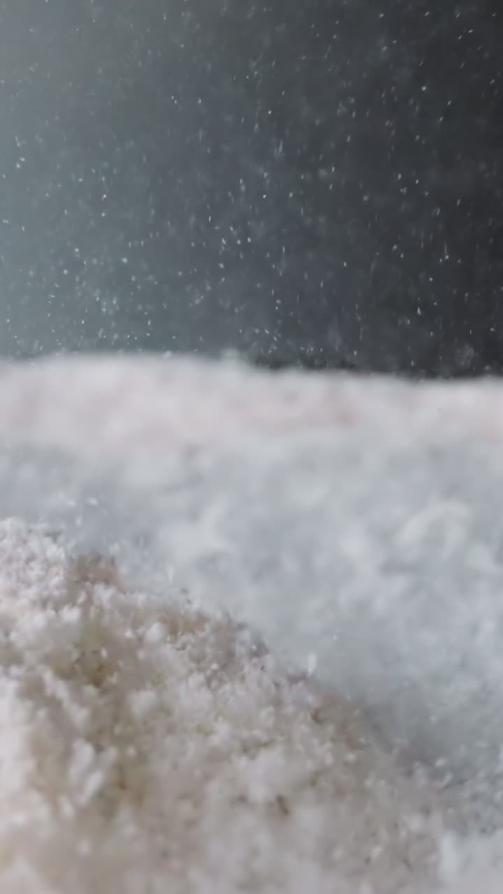 Powdered sugar bounces from vibrations on surface with concavity. Movement of white sweet powder. Food product prepared for use at cooking macro