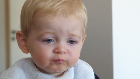 cerca de un niño rubio con ojos azules comiendo comida