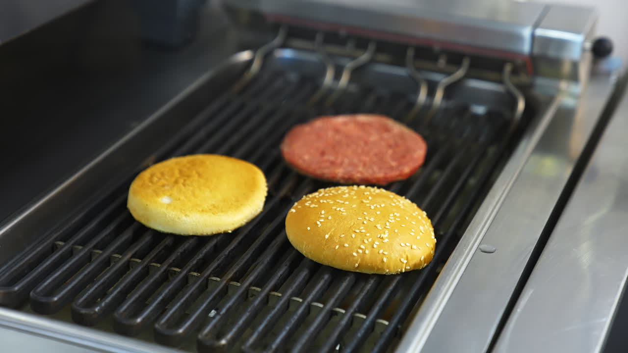 Fresh buns and raw cutlet are grilled on a barbeque. Selective focus on frying process.