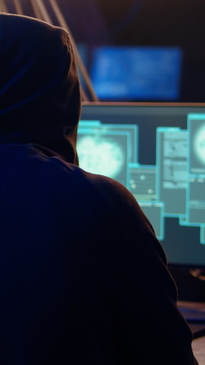 Vertical video Hooded man in underground hideaway hacking computers