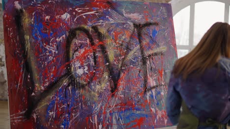 excited girl paints on canvas emotionally dipping hands in paints jar and splashing