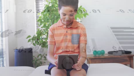 Animation-Von-Grafiken-Und-Währungszeichen-über-Einem-Biracial-Jungen,-Der-Ein-Digitales-Tablet-Nutzt,-Während-Er-Auf-Dem-Sofa-Sitzt