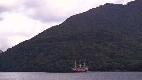 famous hakone pirate tourist ship passing in front of green mountains, showing scale