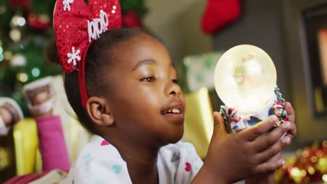 Happy-african-american-girl-playing-with-snow-globe