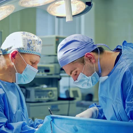 doctors perform an operation using surgical instruments. medical workers in blue protective uniform doing a surgery in the modern operating theater.