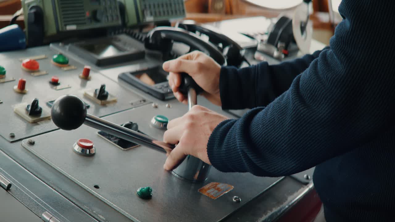 Close-up of sailor operating ship controls and steering lever on bridge