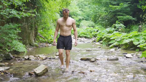 un hombre con zapatillas caminando por un arroyo en el bosque.