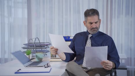 hombre de negocios maduro mirando papeles en su oficina, mirando datos financieros, mirando estados financieros.