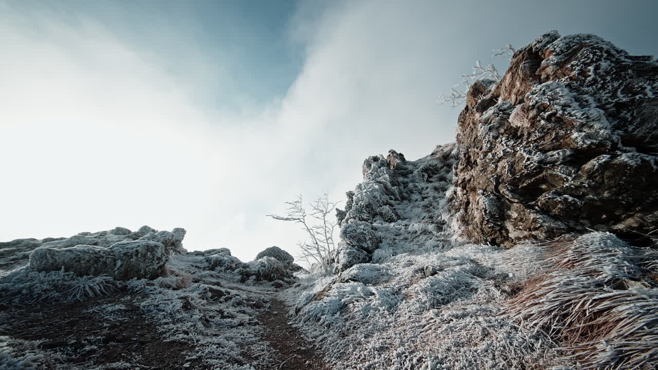 Rocky mountain trail covered with snow, with a person climbing upward.