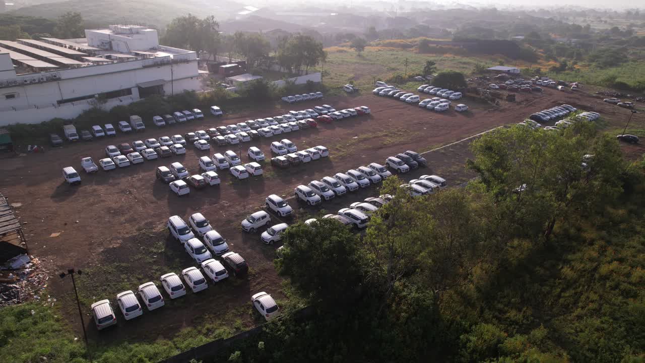 Industrial facility with rooftop solar panels and parked vehicles near green fields covered in dense smog due to air pollution and climate change, Nashik, Maharashtra, Drone shot