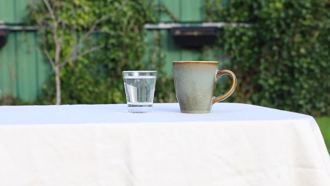 Inquadratura statica di una tazza di caffè e un bicchiere d'acqua.