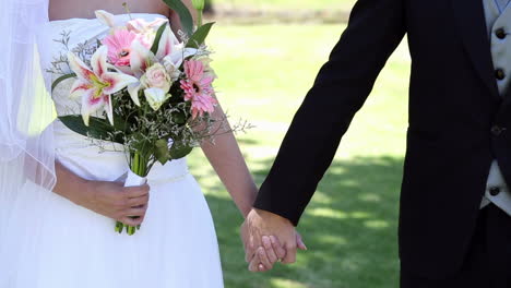 newlyweds standing in the park holding hands