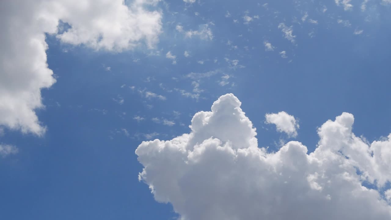 Timelapse of white fluffy clouds moving in the sunny blue sky