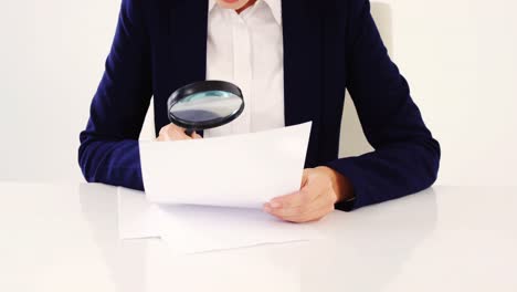 businesswoman checking document with magnifying glass