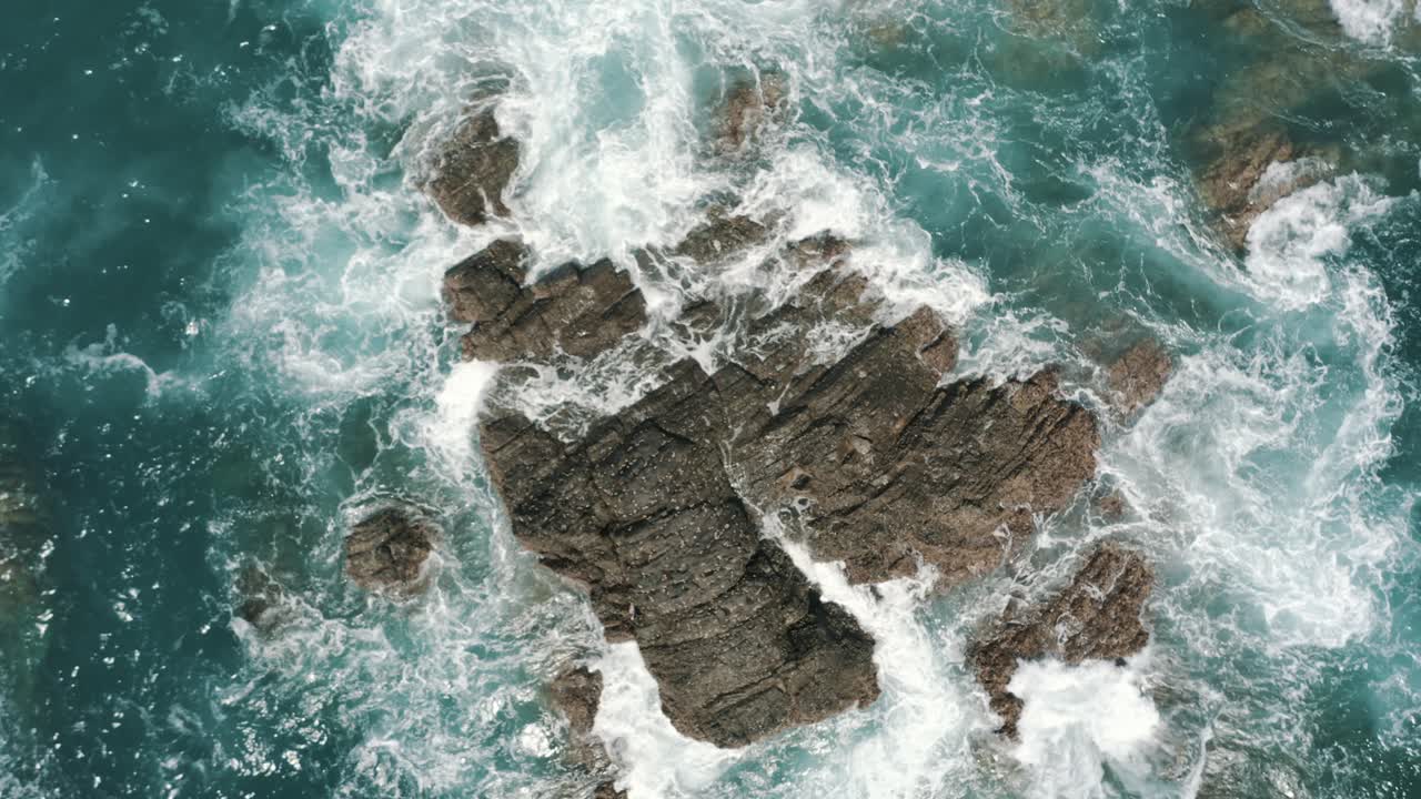 vista superior aérea de drones de olas rompiendo en las rocas en el océano