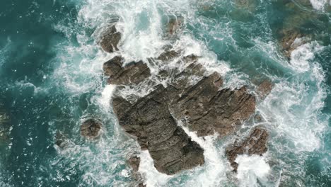 drone aerial top view of waves crashing on the rocks in the ocean