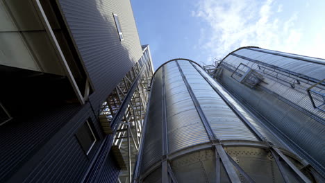 modern granary under blue sky. large aluminum containers for storing grains. exterior of grain elevators. close-up. view from below.