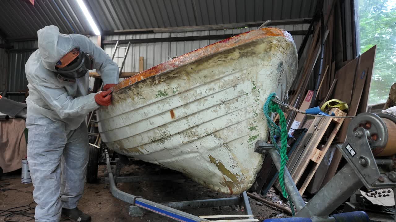 Working on old fiberglass lake boat in workshop