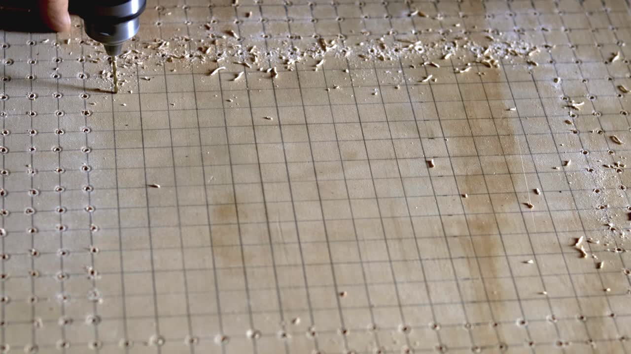 전동 공구를 사용하여 격자선에 따라 구멍 패턴을 뚫습니다.