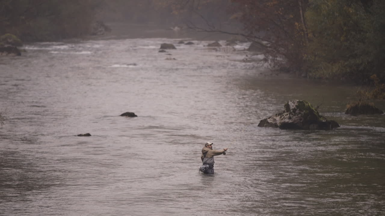 Pescatore a mosca su un fiume autunnale nebbioso