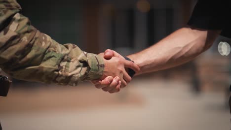 Soldier-and-civilian-arms-shaking-hands-close-up-slow-motion