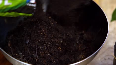 pouring potting soil mix ground earth into metal bowl, orbit around shot