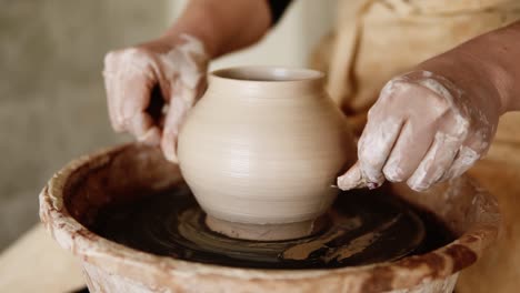 the female potter cuts the base of the vase with a fishing line and split the vase into two half. girl makes pottery from clay close up. making ceramic products from white clay