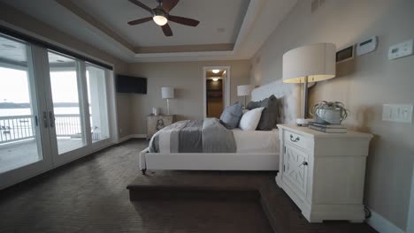 modern white and bright bedroom in a luxury home with large windows leading to a porch