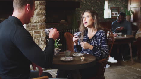 couple sitting at table drinking tea in traditional english holiday hotel