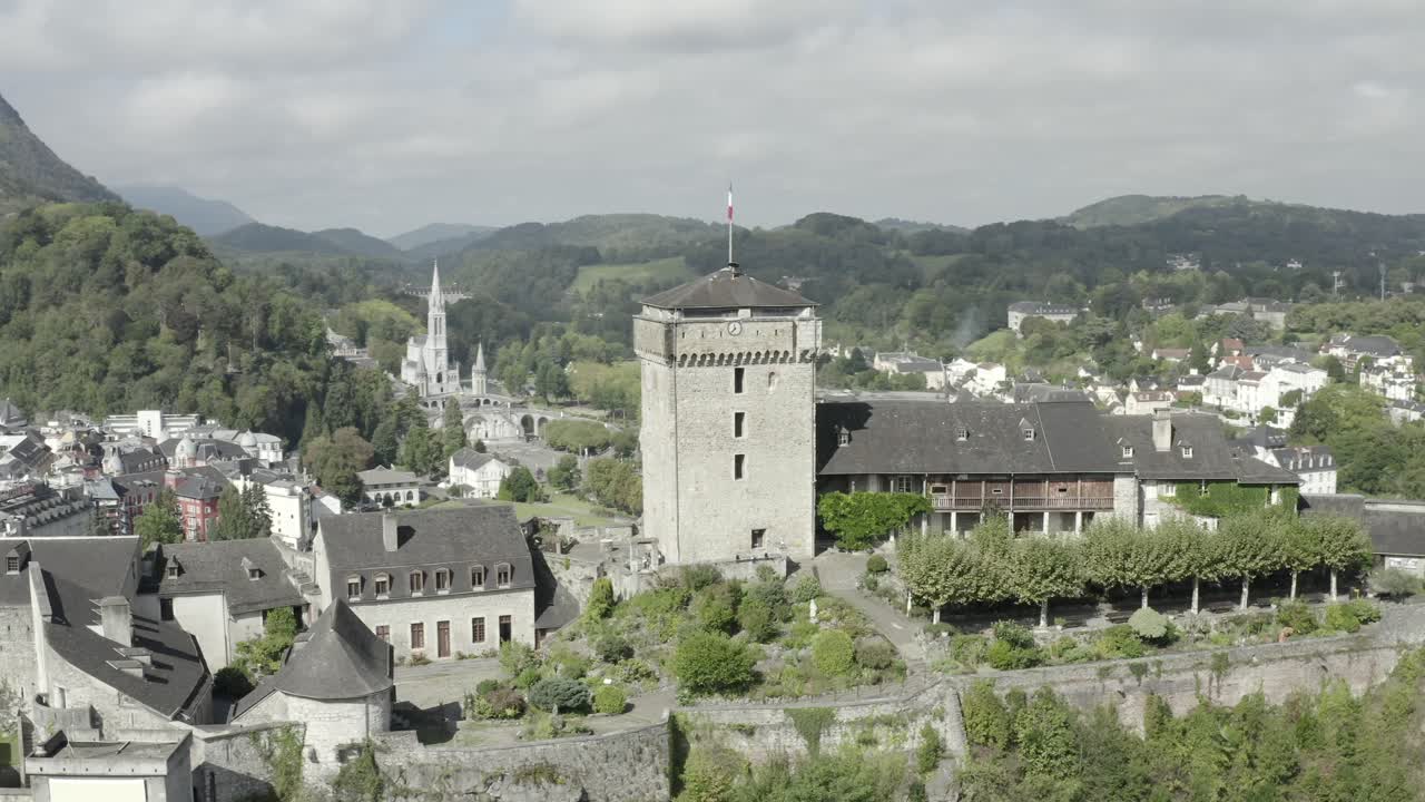Chateau fort de Lourdes castle perched on rock with Sanctuary of Notre-Dame in background, Hautes-Pyrenees in France
