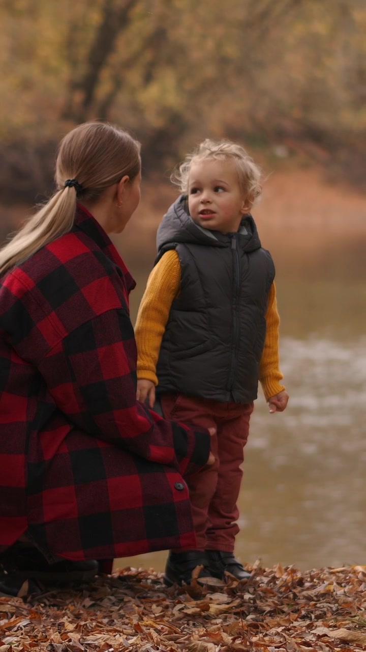 Madre e figlio bambino in piedi accanto a un fiume in autunno