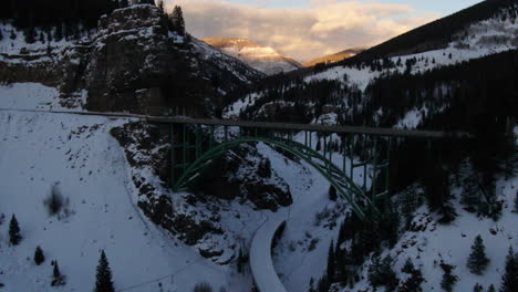 aerial cinematic drone vail avon red cliff iconic bridge in colorado mid winter late sunset backward movement pan up