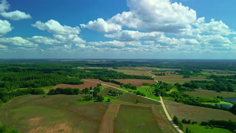 vista of countryside with fields, trees, and lake during sunny summertime