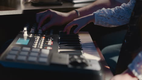 child plays synthesizer with instructor during lesson. student explores musical instrument while mentor configures console. skill of playing instrument