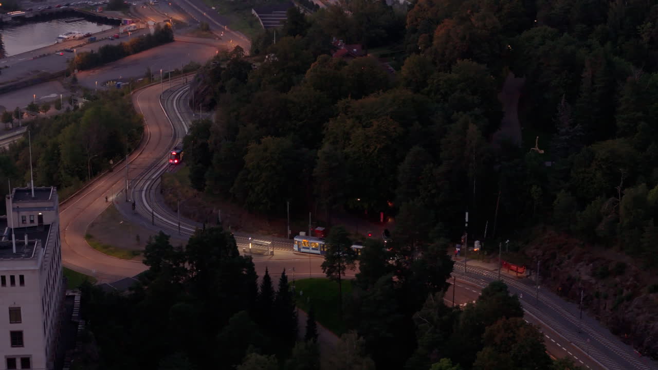Trams pass each other on Kongsveien, by Ekebergsparken, dusk, night