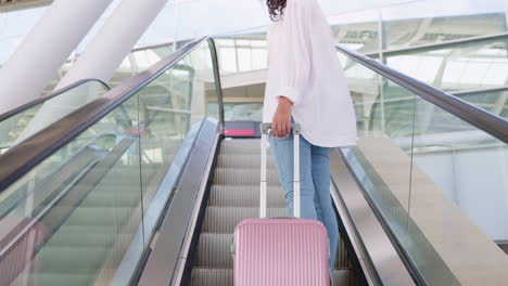 woman with luggage on airport escalator