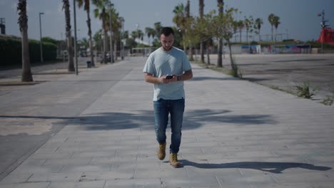 man walking and using smartphone on a city street