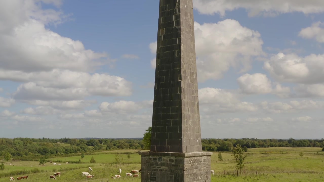Low angle aerial shot of the Killua obelisk, emphasizing its imposing stone structure in County Westmeath, Ireland.
