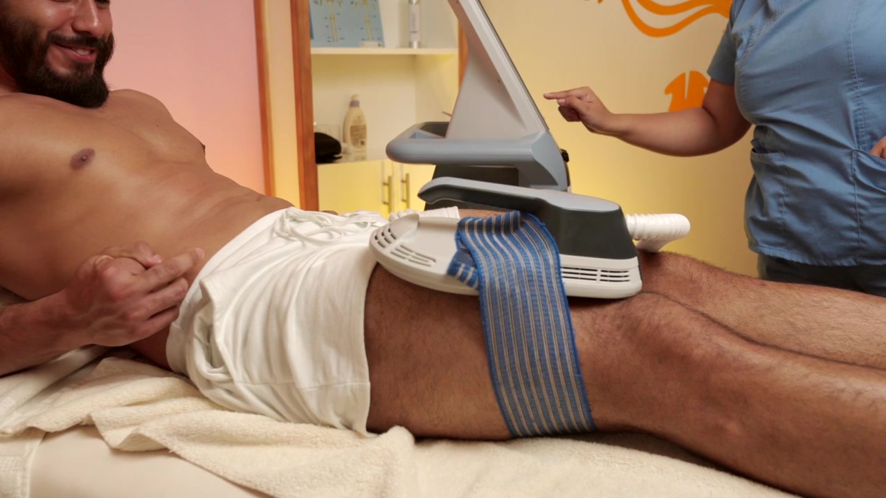 Latin mexican male muscle model guest receive EMS electrical muscle stimulation on legs at spa hotel wellness center high therapy procedure