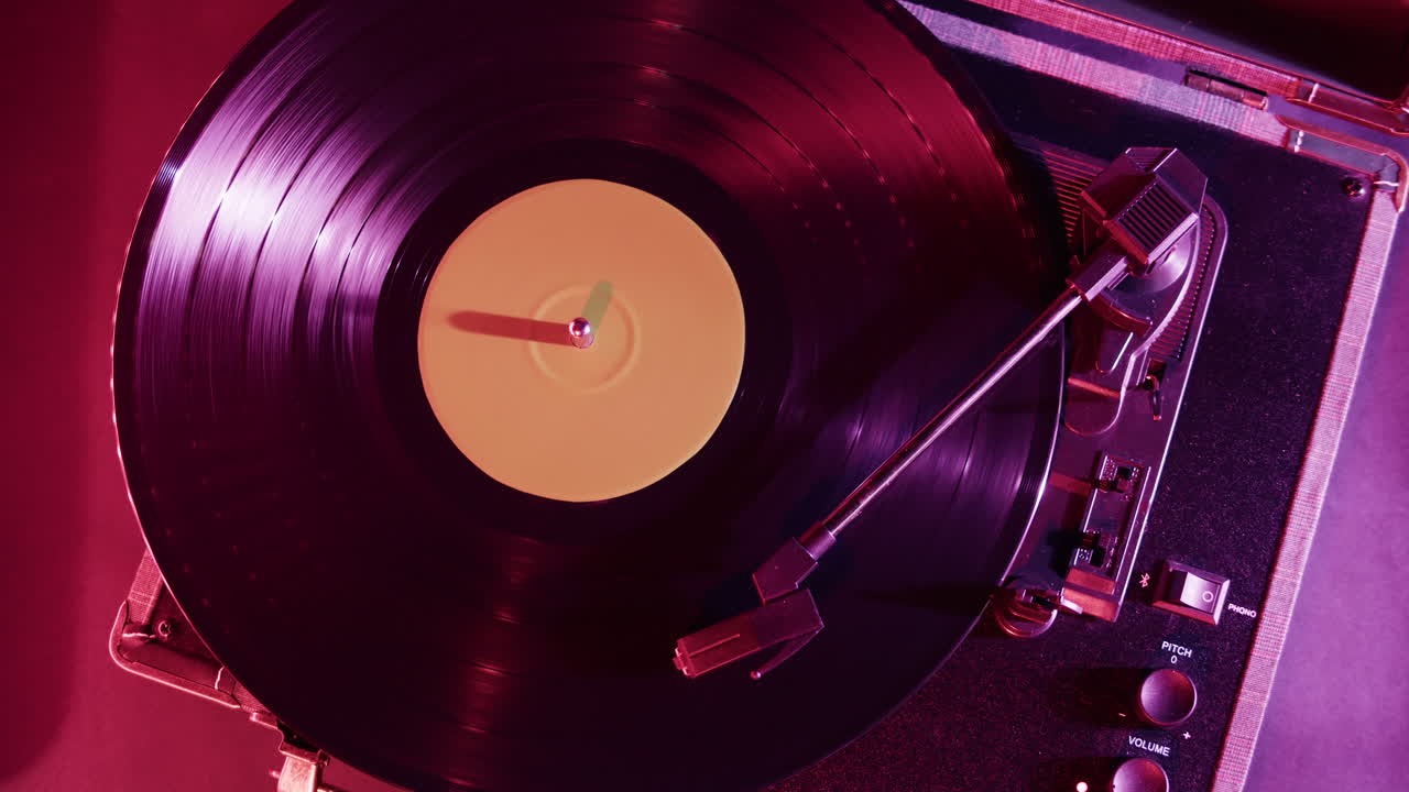 Primo piano di un disco in vinile che gira su un giradischi con luce viola