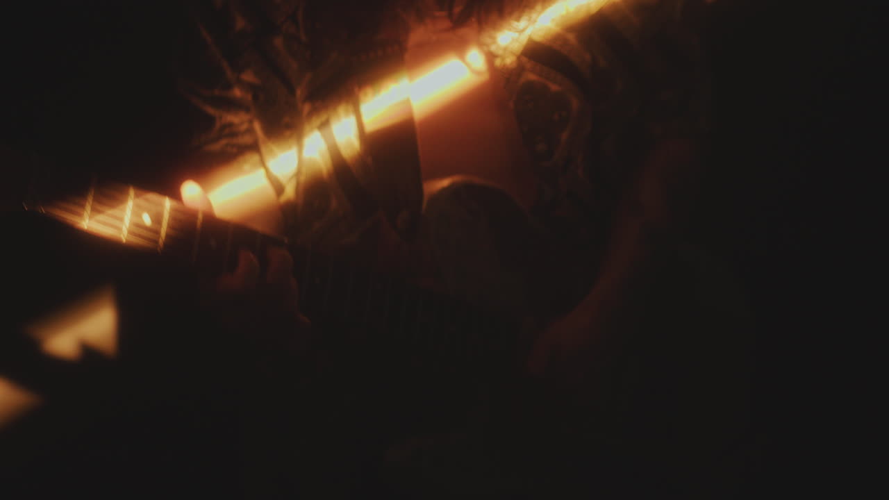 Close-Up of Man Playing Rock Music on the Guitar in Dark Room with Light Beam