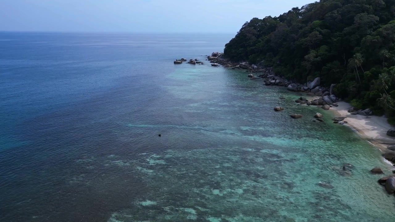 Turquoise water gently washing a sandy beach surrounded by granite rocks and lush tropical vegetation. Marvelous aerial view flight overflight flyover drone