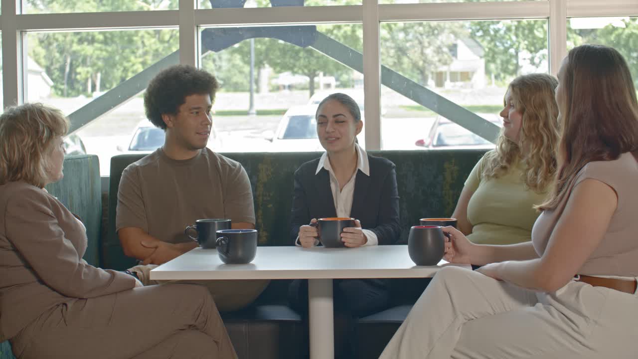 1명의 노인 여성과 4명의 젊은 노동자들과의 사무실 회의 1명의 젊은 여성이 회의를 주도하고 비디오가 천천히 움직이고 있습니다.