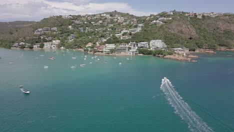 aerial: motorboat speeds toward east head in knysna, south africa