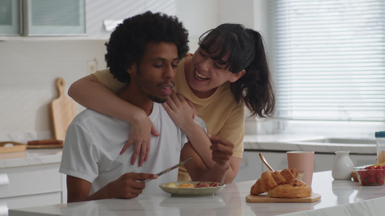 Caucasian Wife Hugging Boyfriend Eating Breakfast at Home