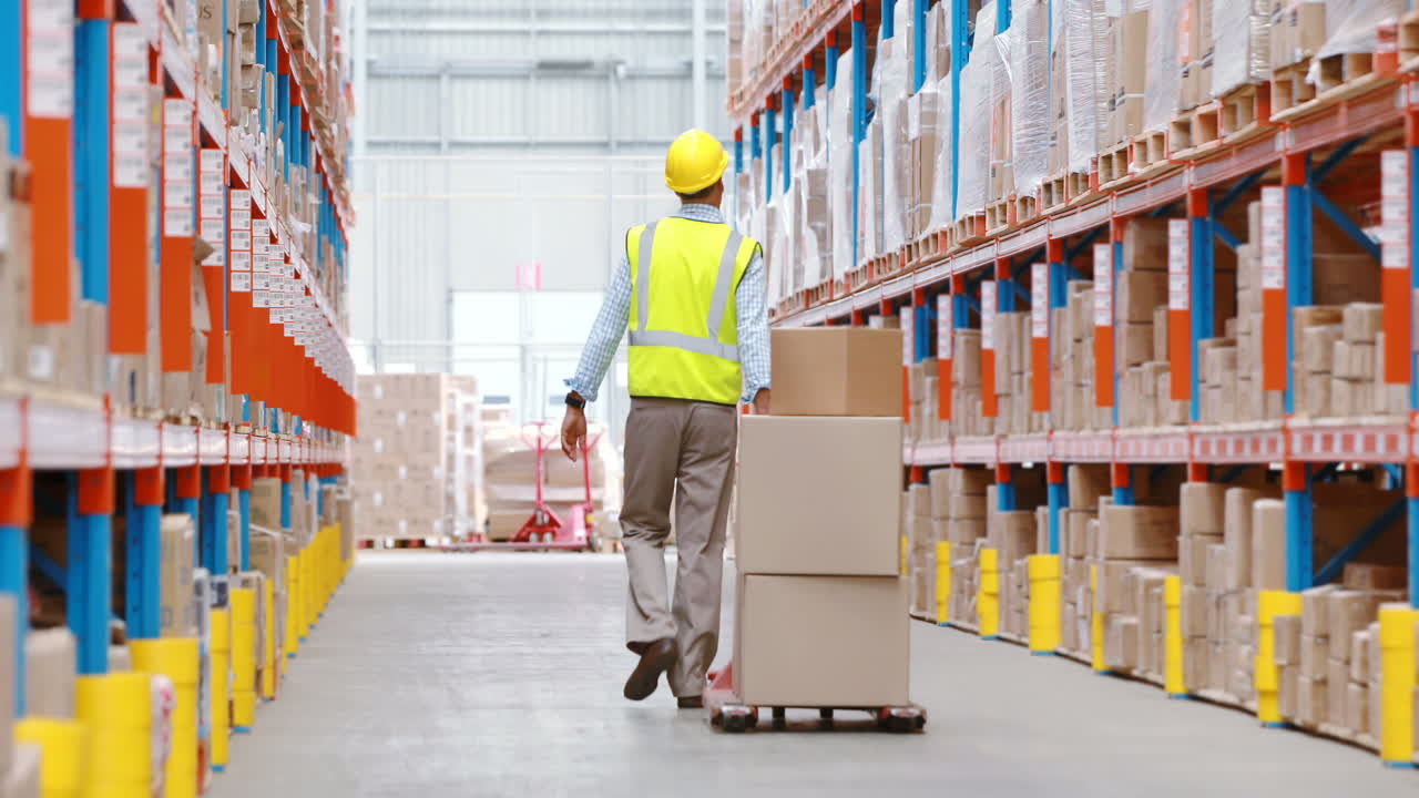 trabajador de almacén tirando de un camión de paletas con cajas de cartón