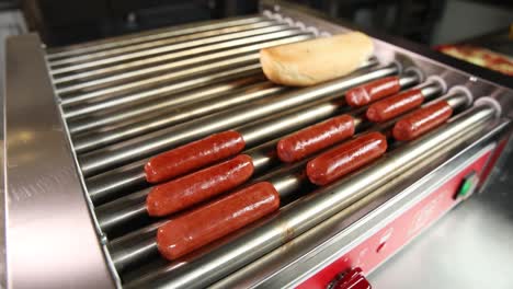 hot dogs cooking on a continuous rotisserie grill